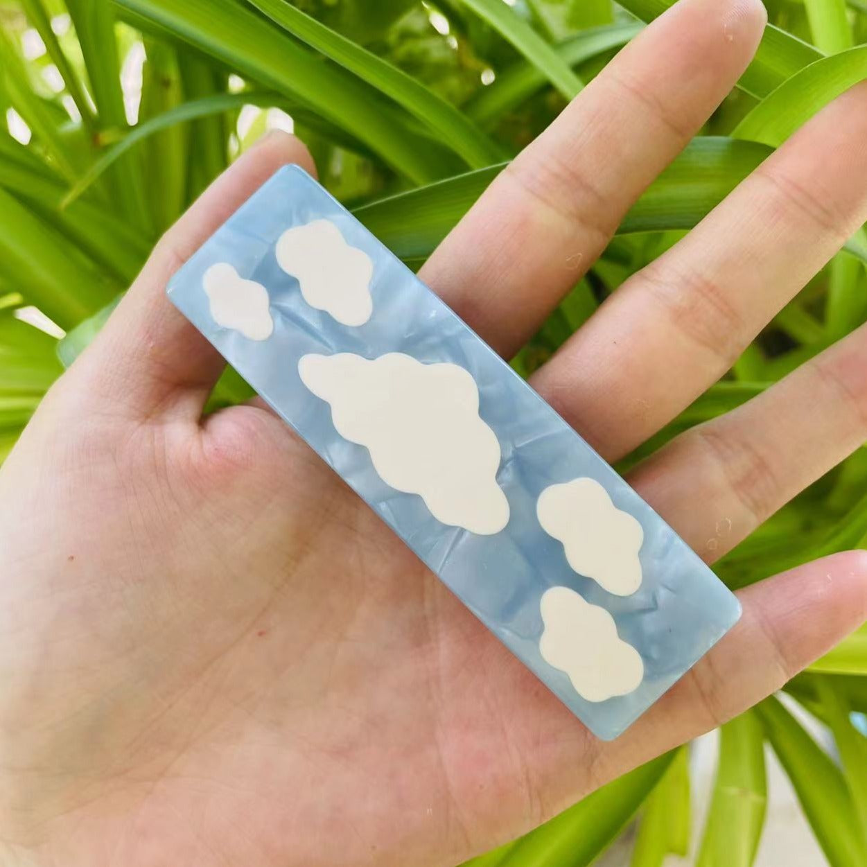 A hand holding the barrette, showcasing its size and design.