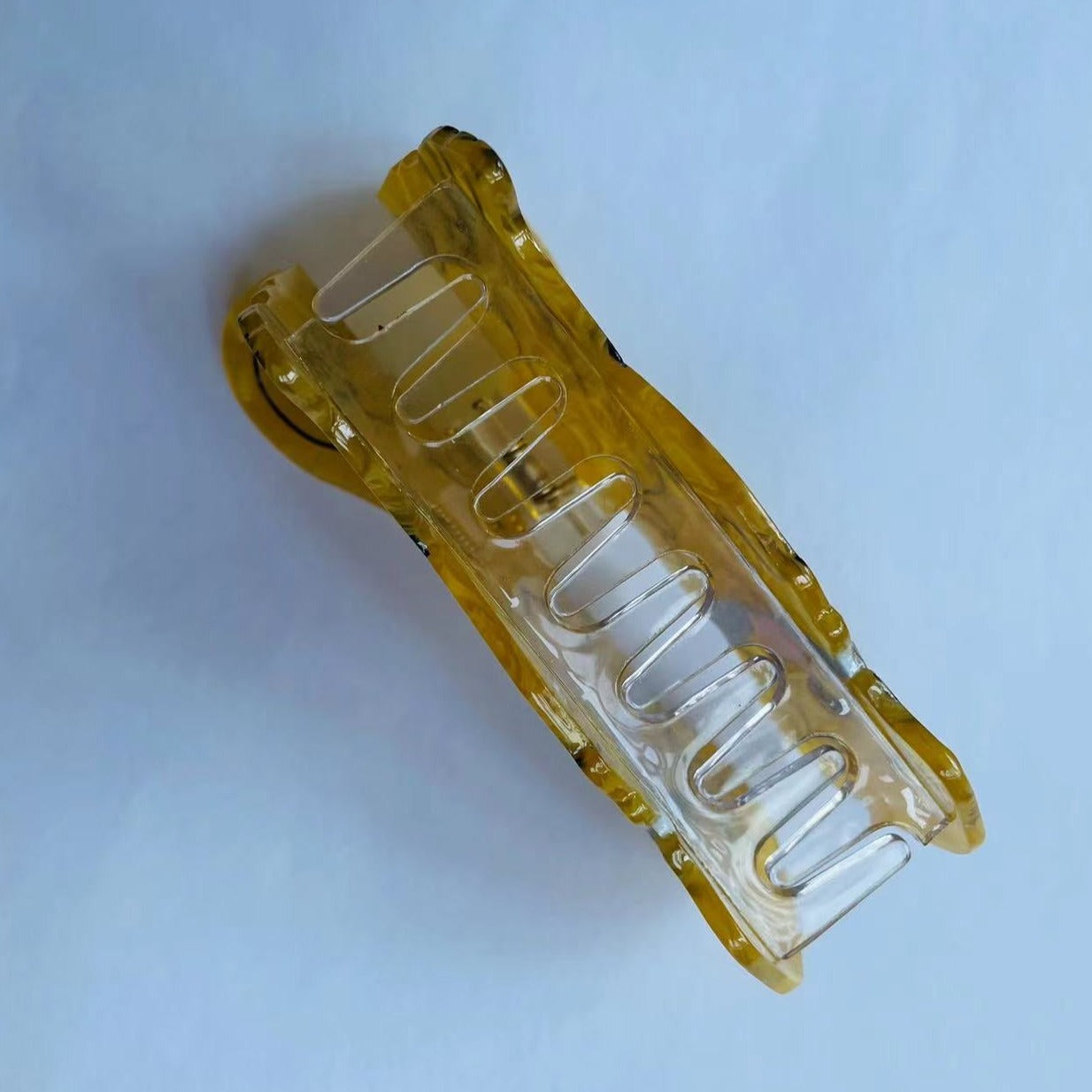 Side view of a yellow marbled acrylic dog-shaped hair clip showing the clamp mechanism