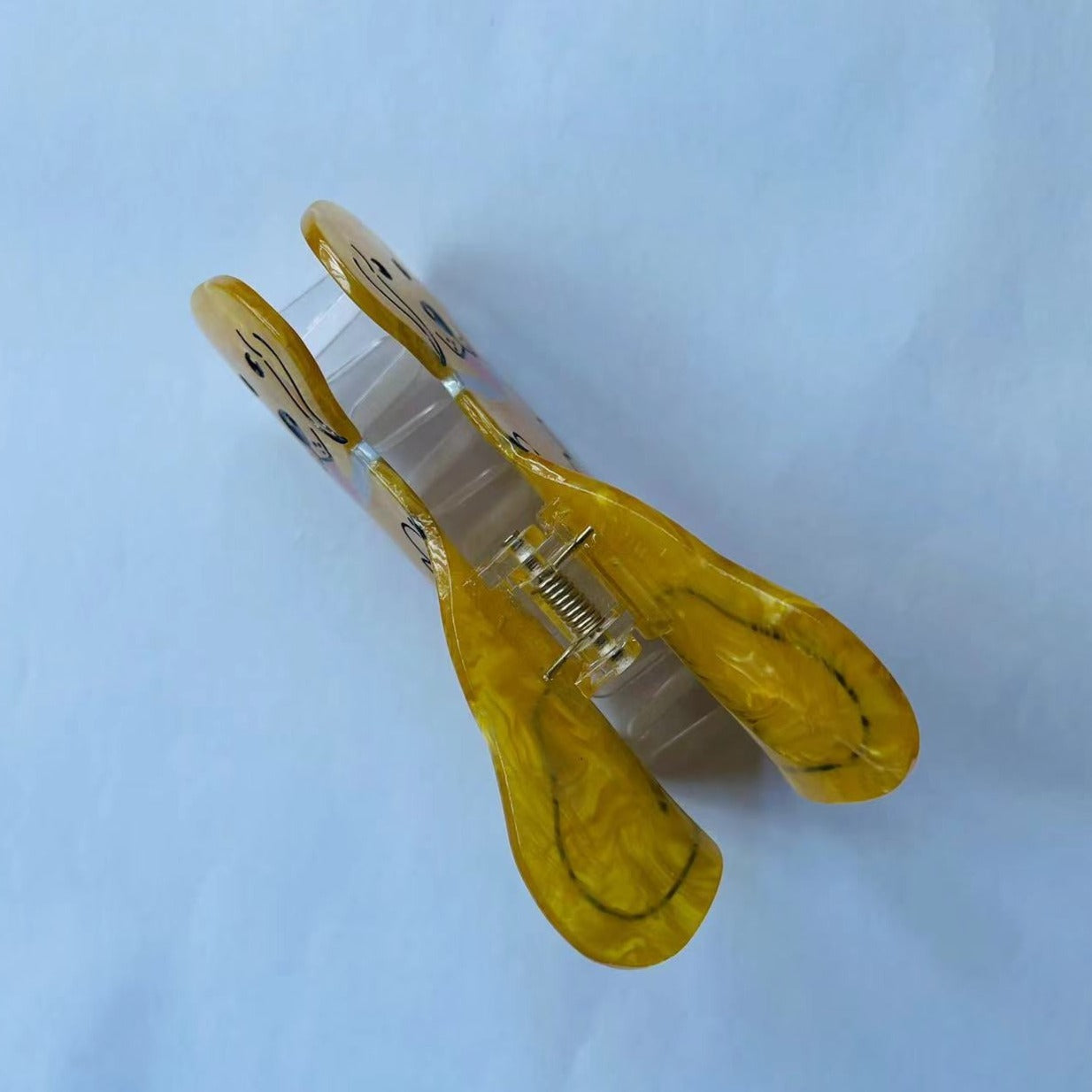 Top view of a yellow marbled acrylic dog-shaped hair clip