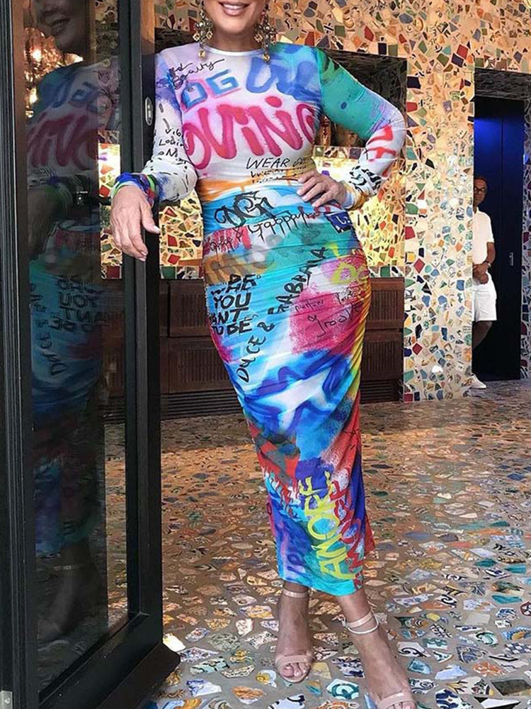 Woman wearing a long-sleeved, graffiti-print, sheer bodycon dress with ruched detailing.