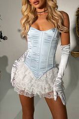Woman wearing a light blue satin corset with white lace trim and white satin gloves, with hands in pockets.