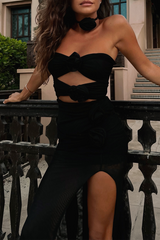 Woman posing in a black strapless top and matching skirt with rose accents.