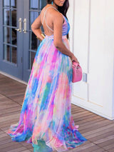 Back view of a woman in a tie-dye maxi dress with thin straps and a flowing skirt.