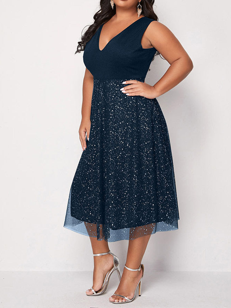 Side view of a woman in a navy blue sleeveless V-neck midi dress with sparkly embellishments and a tulle overlay.