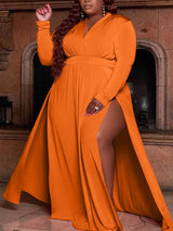 woman wearing a long orange maxi dress with a high slit and long sleeves, showing her hair