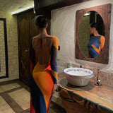 Back view of a woman wearing a long-sleeve dress with an abstract print and an open back.