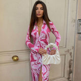 Front view of a woman in a pink and white abstract print bodycon midi dress, holding a white ruched handbag.