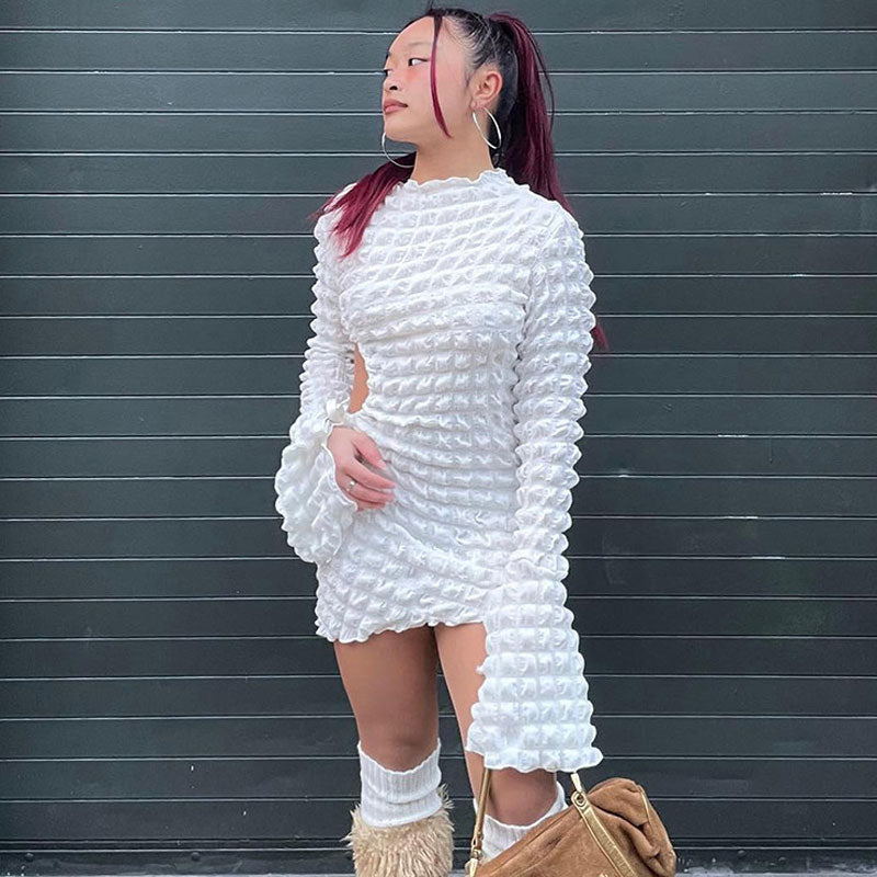 Woman wearing a white textured crinkle fabric bodycon mini dress with long bell sleeves and cut-out details.