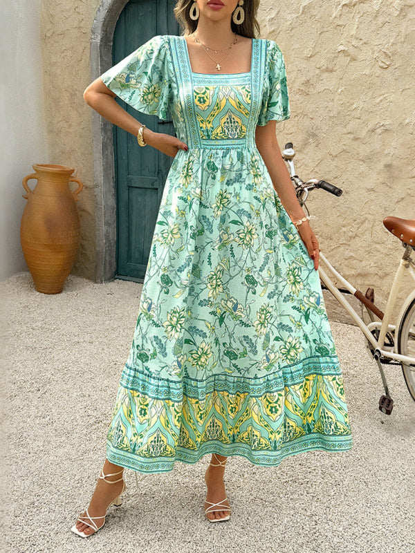 Full body shot of a woman modeling a light green floral print midi dress with a tiered hem.