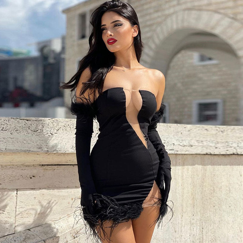 Woman wearing a black strapless mini dress with feather trim and long sleeves, posing outdoors.