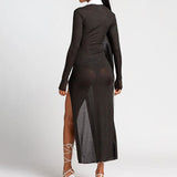 Back view of a woman in a black, sheer, ribbed, long-sleeved maxi dress with a white collared neckline and a high slit.