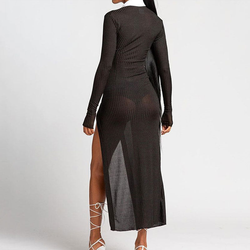 Back view of a woman in a black, sheer, ribbed, long-sleeved maxi dress with a white collared neckline and a high slit.