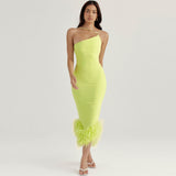 woman in a lime green velvet one-shoulder dress with feather trim