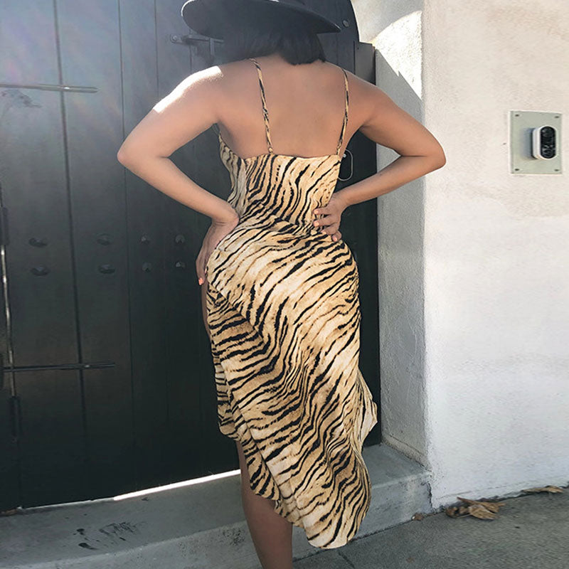 Back view of a woman wearing a tiger print slip dress with a high slit and a black hat.