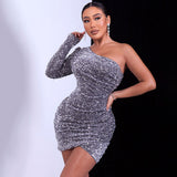 Full-body view of a woman in a silver sequined one-shoulder mini dress with long sleeves.