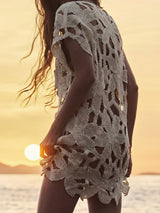 Close-up of the detailed open-knit pattern of the cream-colored tunic.