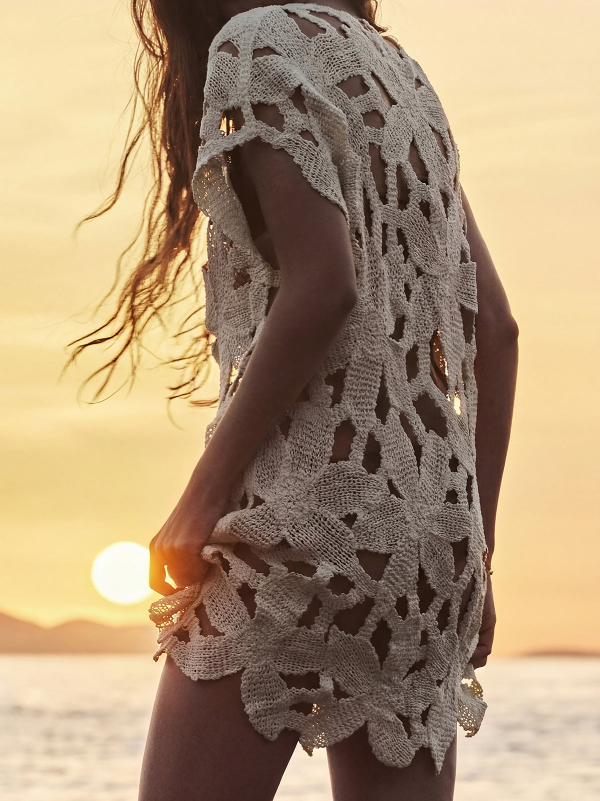 Close-up of the detailed open-knit pattern of the cream-colored tunic.