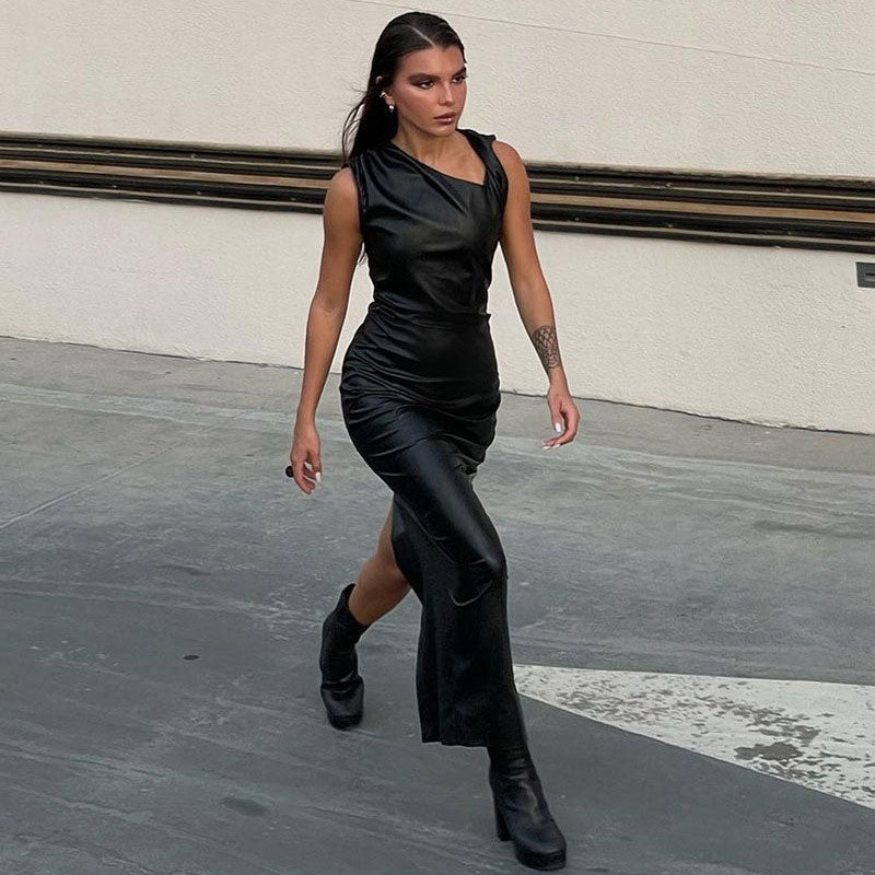 woman walking in a black faux leather column dress with an asymmetrical neckline and ruching detail