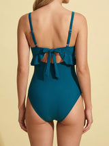 Woman modeling a teal one-piece swimsuit from the back with a tie closure