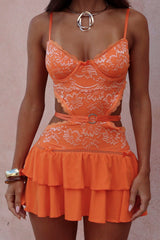 Close-up of an orange lace and fabric set with a sweetheart neckline and tiered skirt.