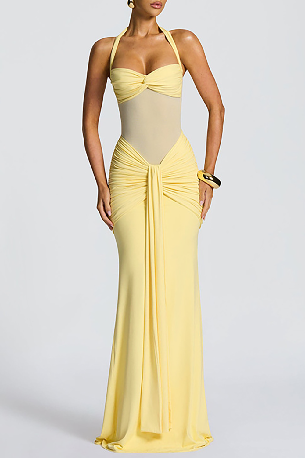 Full-length view of a woman in a yellow ruched halter neck gown.
