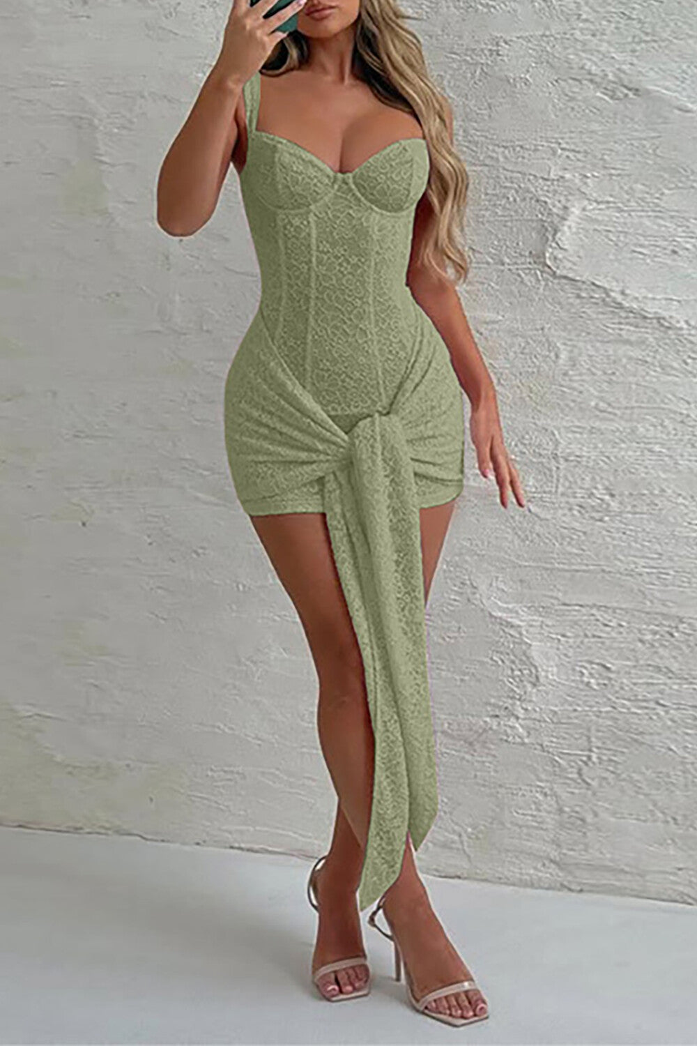 Woman wearing a light green lace corset dress with a draped skirt