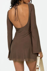 Back view of a woman wearing a brown open-back mini dress with tie closure and bell sleeves.