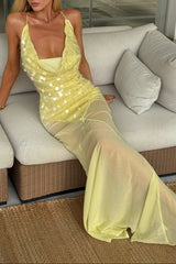 A woman is seated on a sofa, showcasing a yellow sequin and chiffon maxi dress.