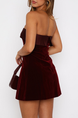 Back view of a woman in a burgundy velvet strapless mini dress