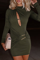 Close-up of a woman in an olive green mini dress, holding a light-colored clutch.