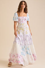 Woman wearing a white floral print maxi dress with puff sleeves and a square neckline, standing and posing.