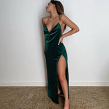 Woman posing in a sleek, dark green velvet maxi dress with a daring thigh-high slit.