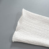 Close-up of white textured crinkle knit fabric with a wavy pattern.