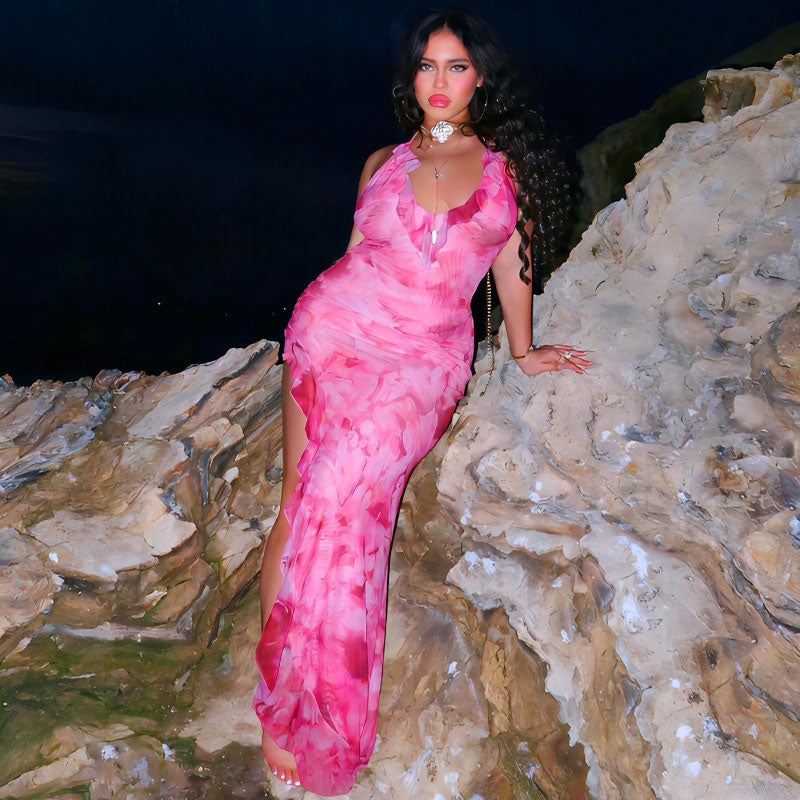 woman in pink floral print halter maxi dress leaning on rocks at night