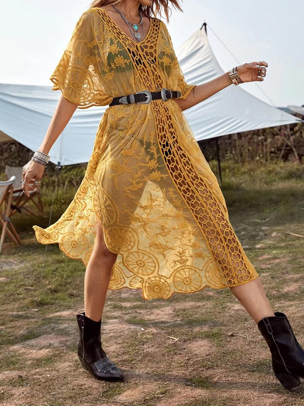 Woman wearing a yellow lace beach cover-up with a belt and boots outdoors.