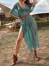 Woman wearing a teal lace beach cover-up with a belt and boots outdoors.