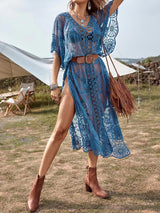 Woman wearing a blue lace beach cover-up with a belt and handbag outdoors.