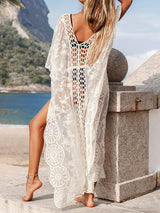 Back view of a woman wearing a white lace beach cover-up at the beach.