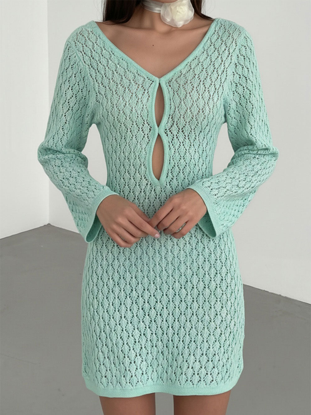 woman wearing a mint green crochet knit mini dress with long bell sleeves and a keyhole neckline