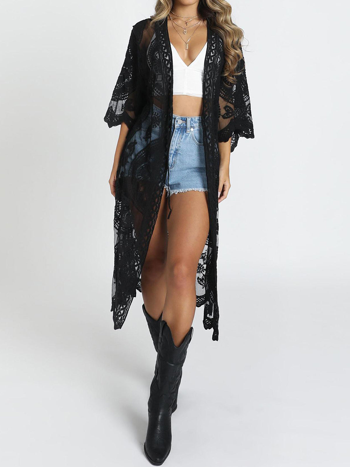 Woman wearing a black lace kimono over a white crop top and denim shorts