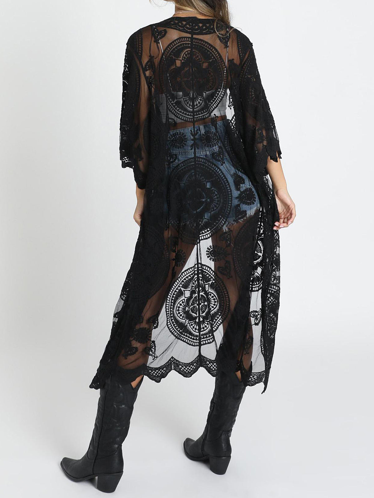 Back view of a woman wearing a black lace kimono over a white crop top and denim shorts