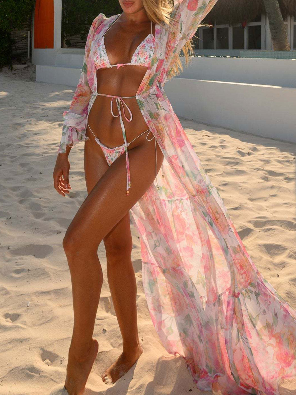 woman wearing a floral print sheer maxi kimono over a bikini on a beach