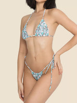 Side view of a model wearing a blue and white patterned triangle bikini set with halter neck and tie sides.