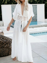woman wearing a white sheer maxi cover-up with lace detailing at the waist and a plunging neckline