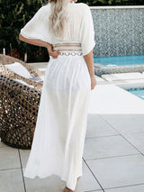 back view of a woman wearing a white sheer maxi cover-up, showing the lace detailing at the waist
