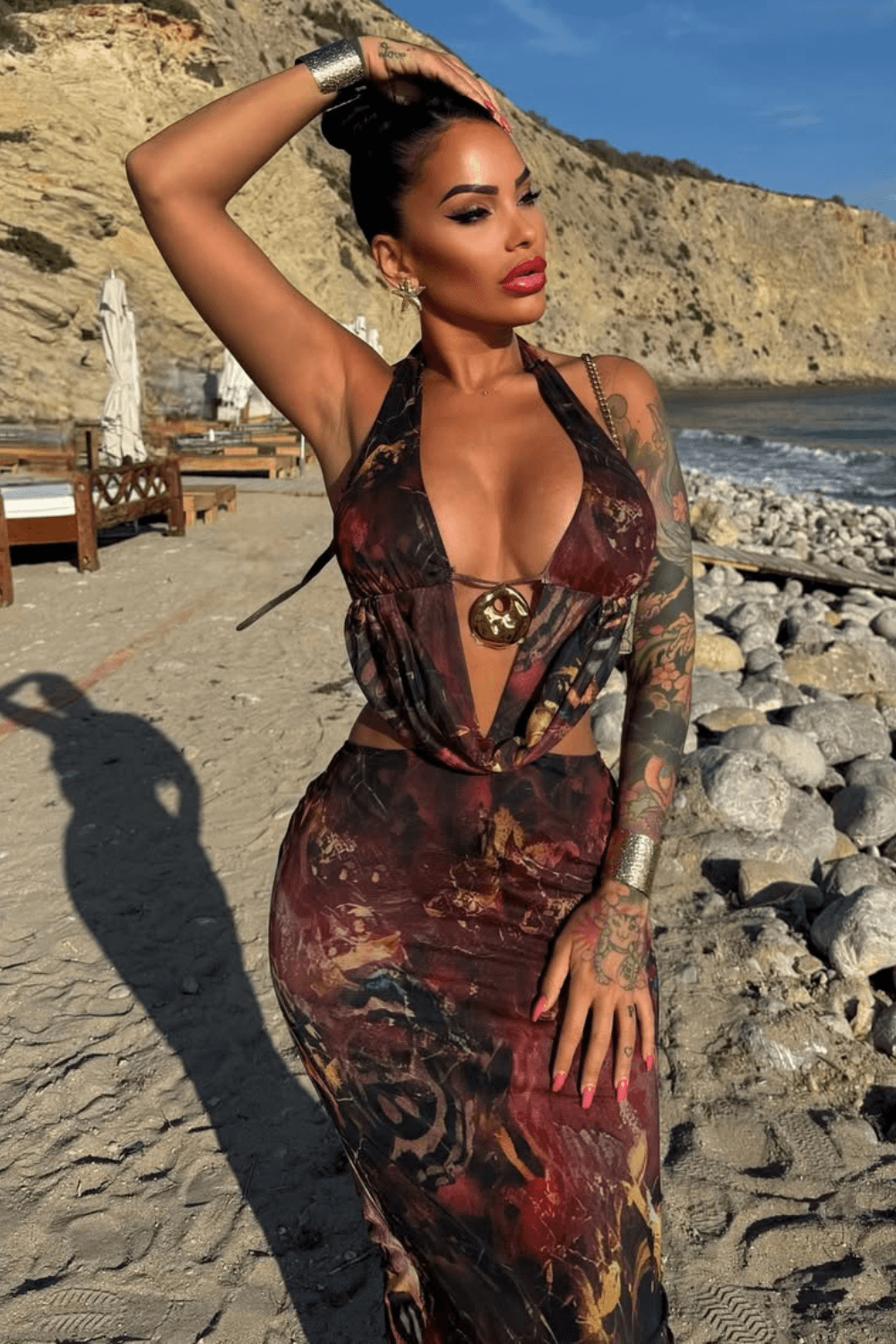 Woman with her hand on her head wearing a printed halter neck maxi dress