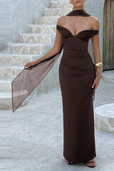 Woman in a light pink off-the-shoulder formal gown with a ruched bodice and draped fabric, standing on stairs.