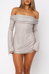 Front view of a woman in a shimmering off-the-shoulder mini dress with bell sleeves.