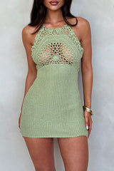 Woman wearing a green crochet halter mini dress standing against a wall.