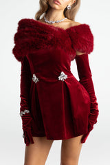 Model wearing a red velvet off-the-shoulder mini dress with feather trim and long gloves.